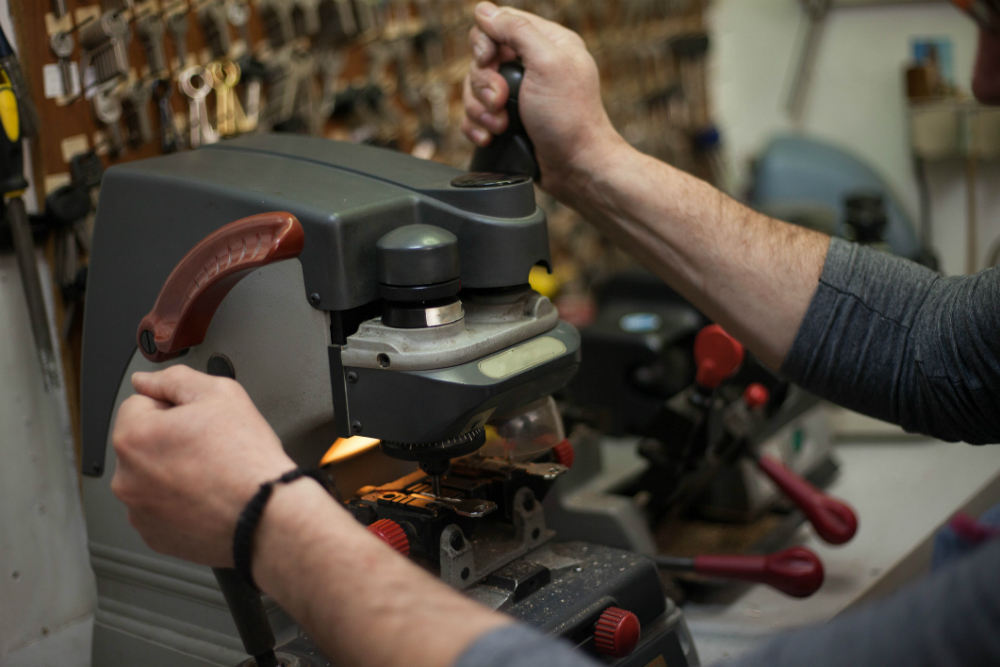Locksmith Inc expert duplicating a car key in our Southfield MI shop using a professional key cutting machine